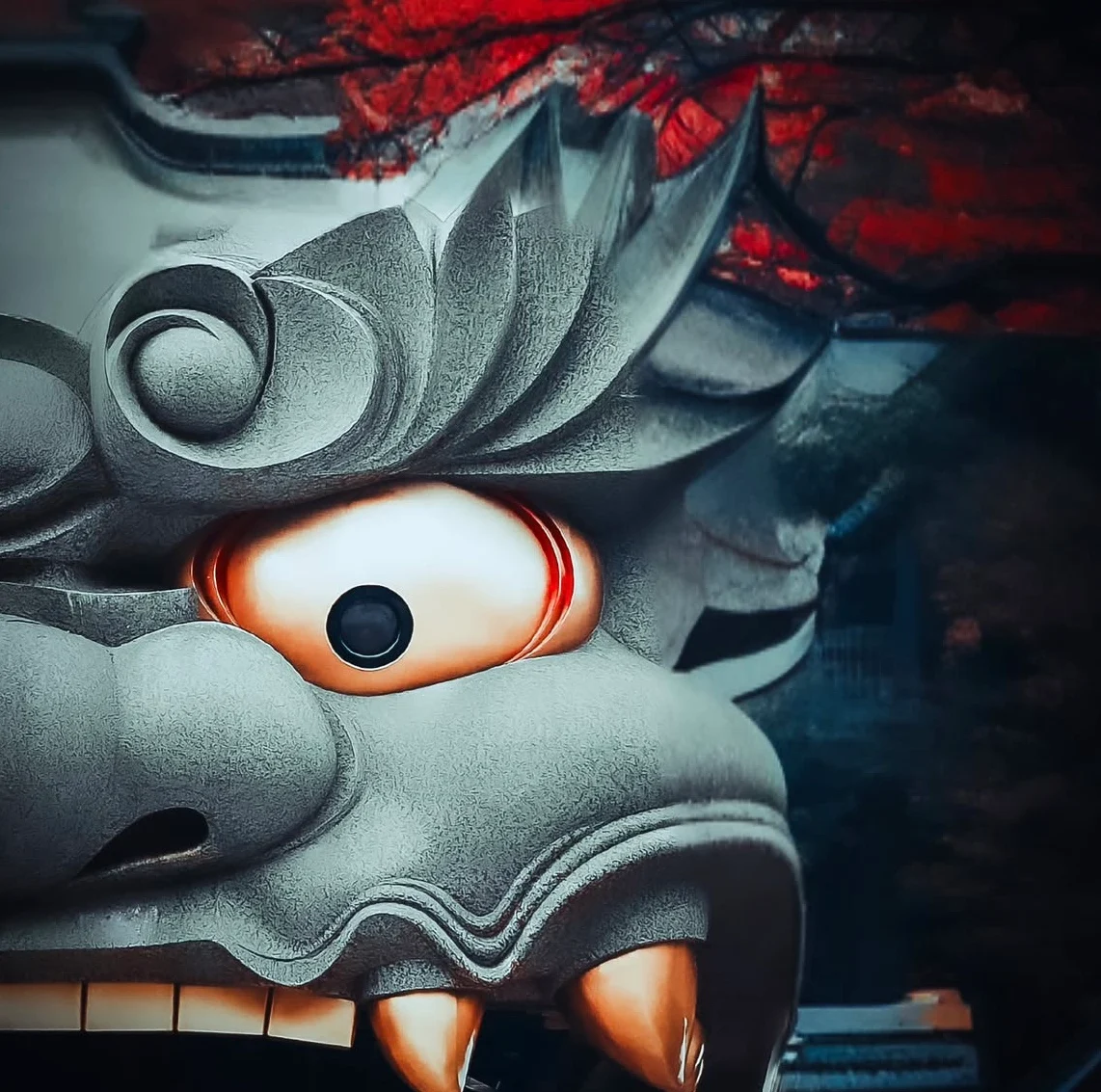 The giant stone lion head of Namba Yasaka Shrine filling the frame, one gilded eye lit against red autumn maple.